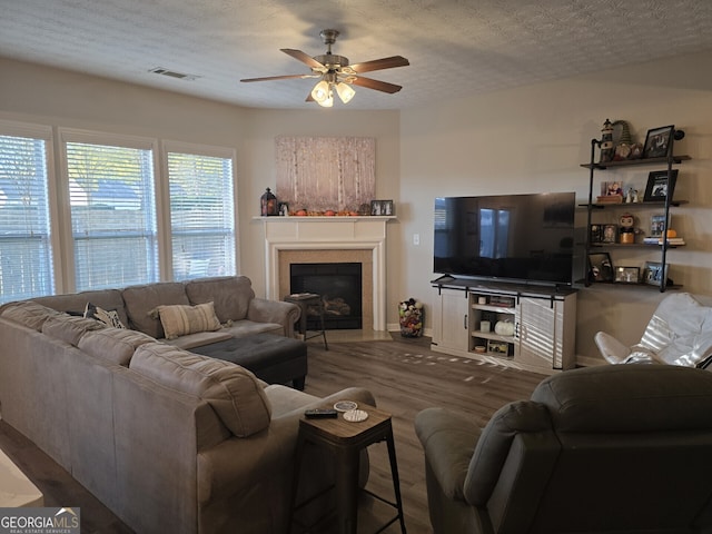 living room with a textured ceiling, ceiling fan, and dark wood-type flooring