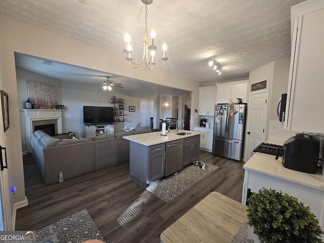 kitchen featuring a kitchen island with sink, hanging light fixtures, sink, white cabinetry, and stainless steel appliances