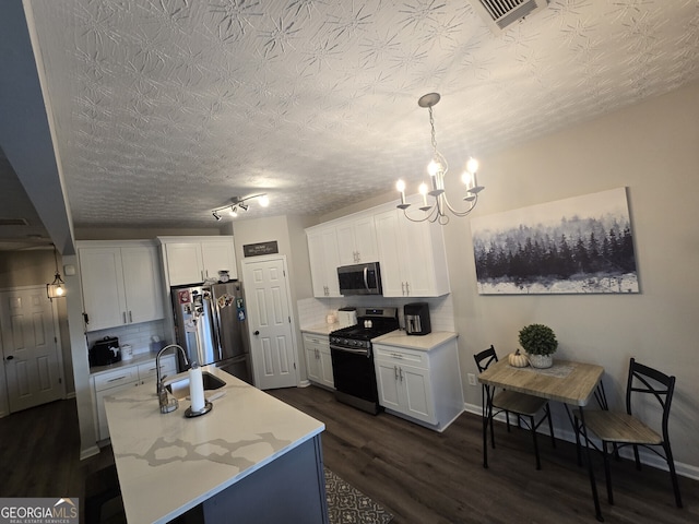 kitchen featuring white cabinets, decorative light fixtures, appliances with stainless steel finishes, and tasteful backsplash