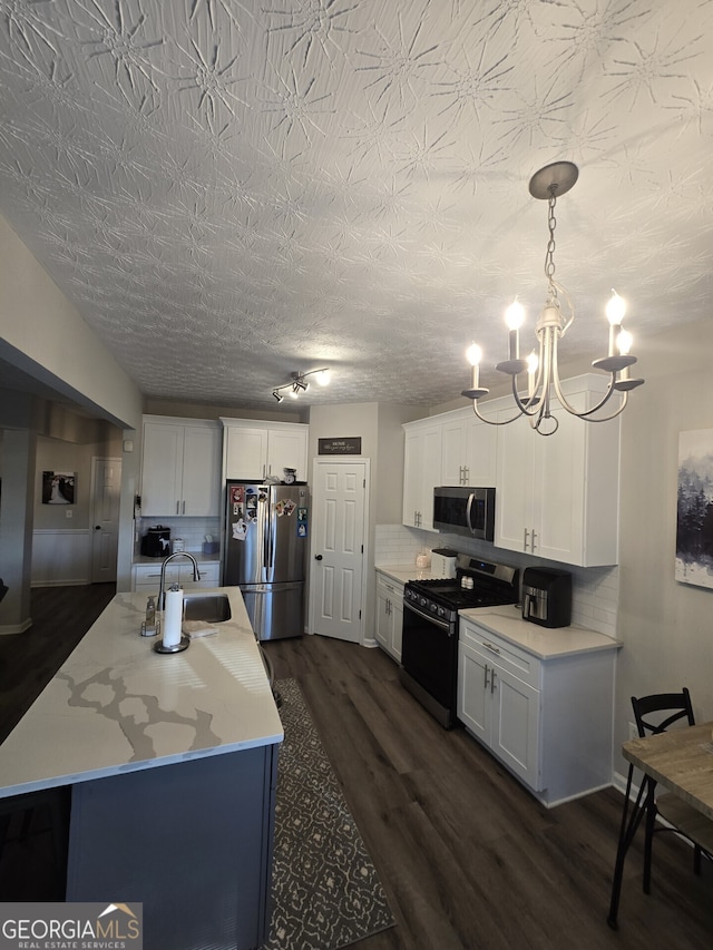 kitchen featuring backsplash, white cabinetry, stainless steel appliances, and decorative light fixtures