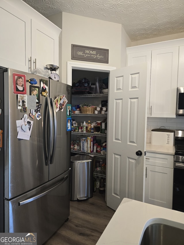 kitchen with white cabinetry, dark wood-type flooring, a textured ceiling, and appliances with stainless steel finishes