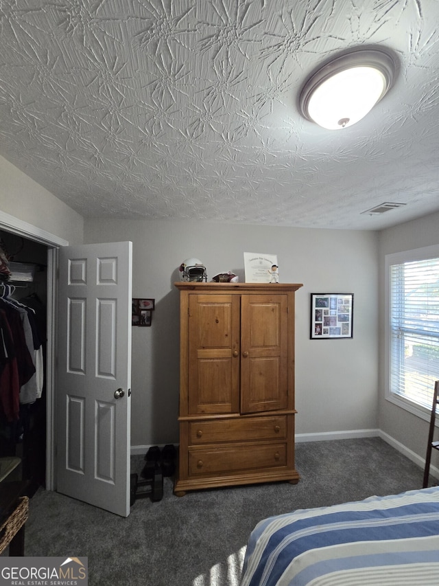 carpeted bedroom featuring a textured ceiling and a closet