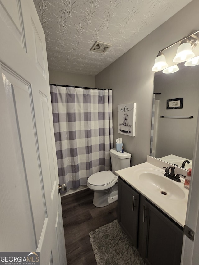 bathroom with vanity, toilet, wood-type flooring, and a textured ceiling