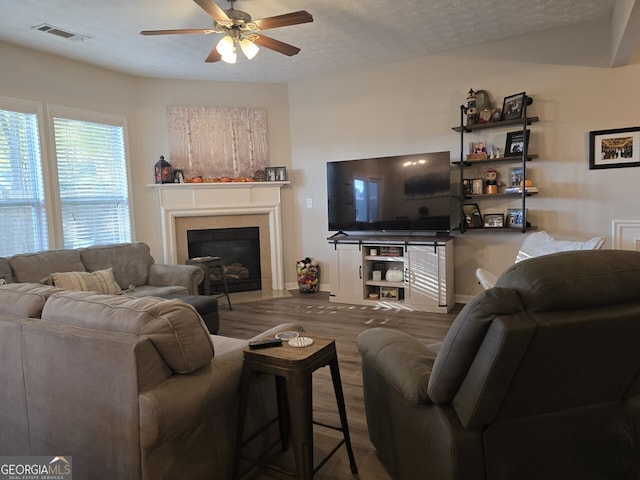 living room with a textured ceiling, hardwood / wood-style flooring, and ceiling fan