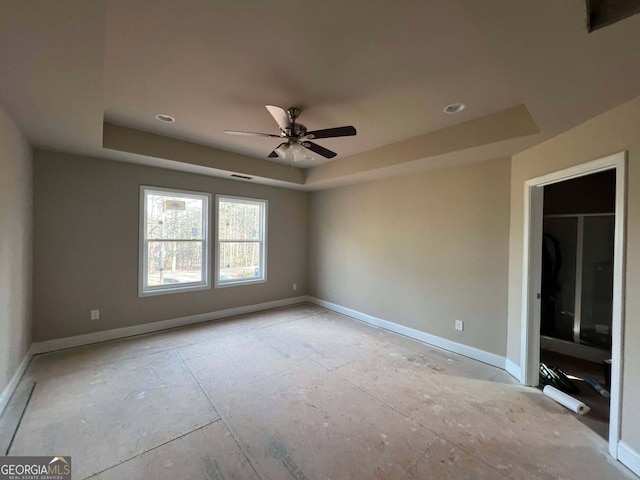 spare room with ceiling fan and a tray ceiling