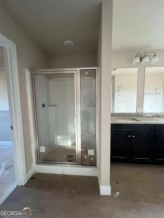 bathroom with vanity, concrete flooring, and a shower with door