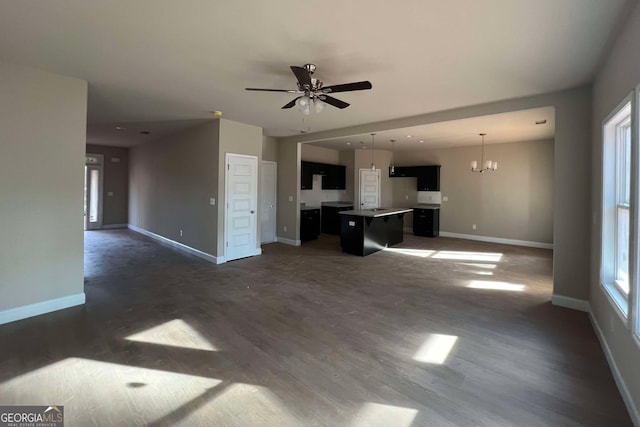 unfurnished living room with ceiling fan with notable chandelier and dark hardwood / wood-style floors