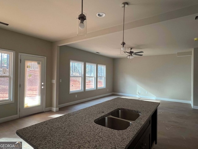 kitchen with dark stone countertops, sink, a kitchen island with sink, and decorative light fixtures