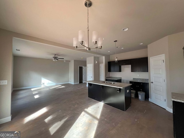 kitchen with a kitchen island with sink, decorative light fixtures, sink, a breakfast bar area, and ceiling fan with notable chandelier