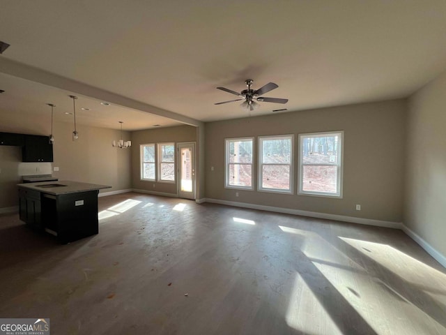 unfurnished living room with ceiling fan with notable chandelier