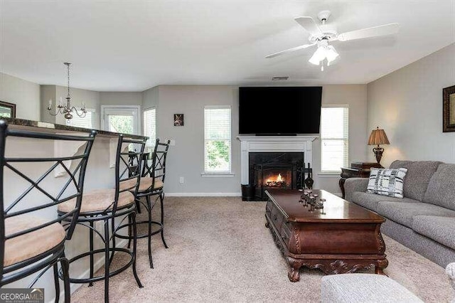 living room featuring ceiling fan with notable chandelier and light colored carpet