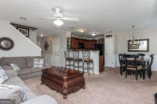 living room with ceiling fan with notable chandelier and light carpet