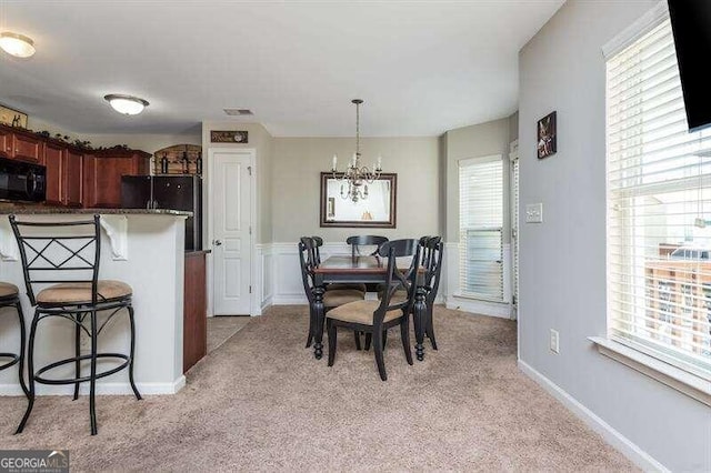 carpeted dining room featuring a notable chandelier