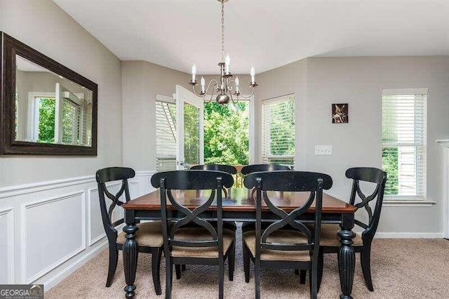 carpeted dining area featuring plenty of natural light and a notable chandelier