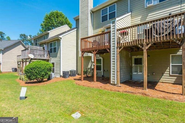 rear view of property featuring a yard, cooling unit, and a wooden deck