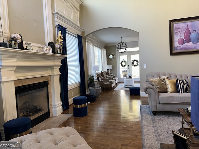 living room featuring a tiled fireplace, crown molding, hardwood / wood-style floors, and an inviting chandelier