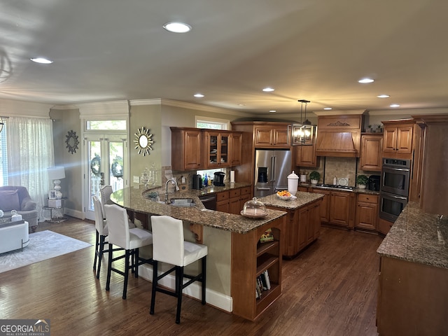 kitchen with dark wood-type flooring, hanging light fixtures, kitchen peninsula, decorative backsplash, and appliances with stainless steel finishes