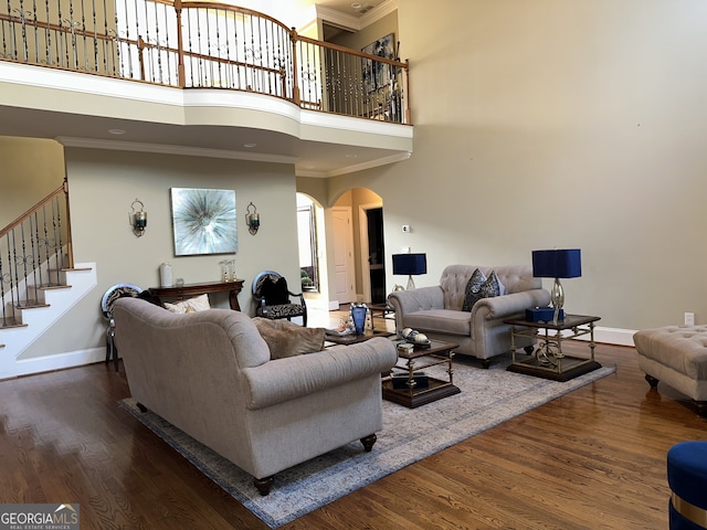 living room featuring crown molding, a towering ceiling, and dark wood-type flooring