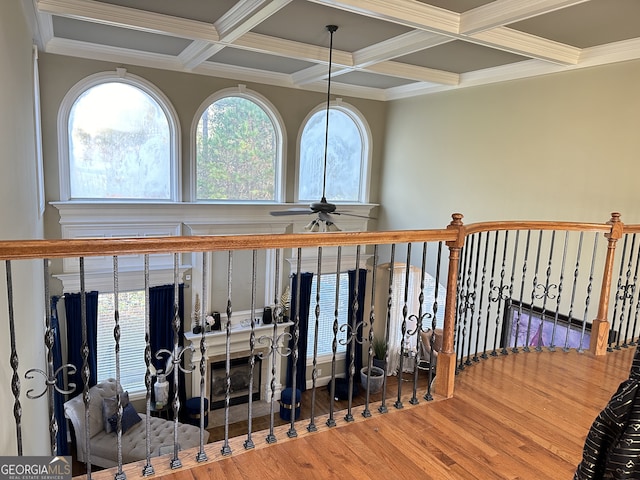 interior space with ceiling fan, coffered ceiling, beamed ceiling, crown molding, and wood-type flooring