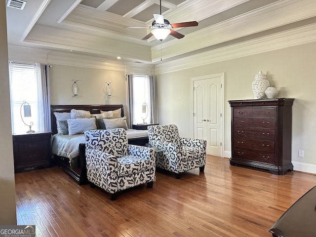 bedroom featuring hardwood / wood-style floors, ceiling fan, ornamental molding, and a tray ceiling