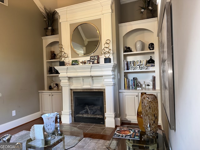 living room featuring built in shelves, a fireplace, and dark wood-type flooring