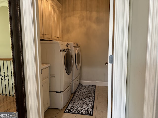 clothes washing area featuring cabinets, light tile patterned floors, and washer and clothes dryer