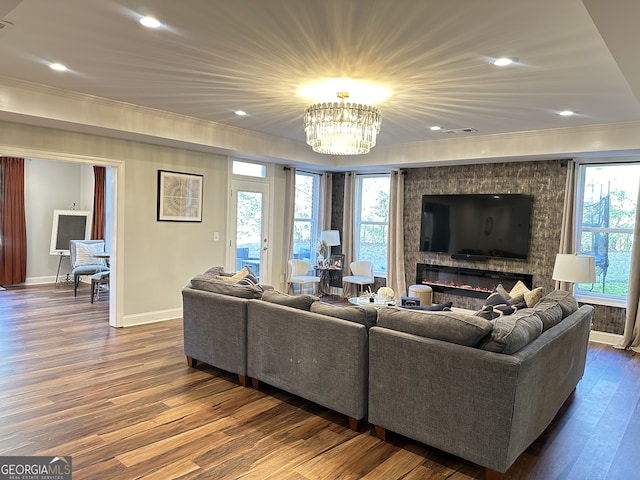 living room with dark hardwood / wood-style floors, plenty of natural light, ornamental molding, and an inviting chandelier