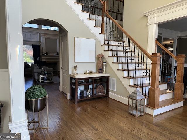 stairway with hardwood / wood-style flooring, a towering ceiling, and crown molding