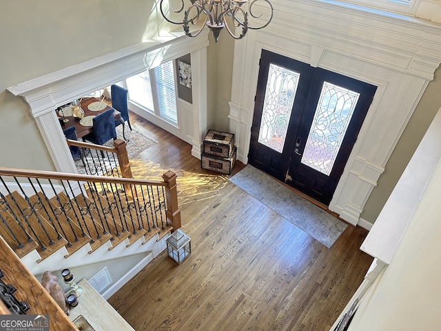 foyer with a notable chandelier, plenty of natural light, wood-type flooring, and french doors