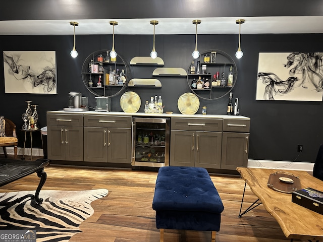 bar with decorative light fixtures, gray cabinets, light wood-type flooring, and beverage cooler