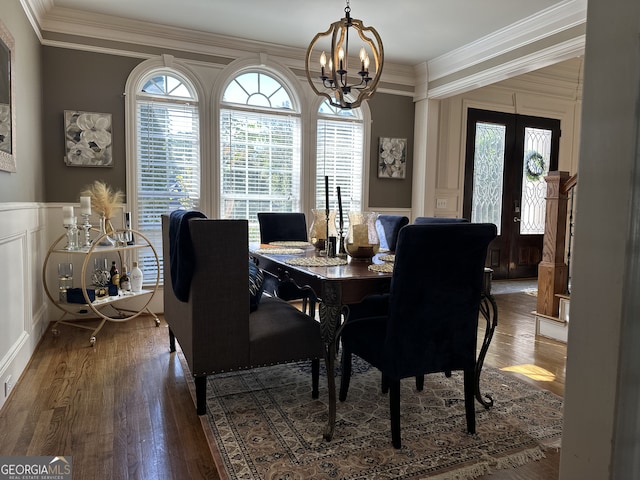 dining space featuring hardwood / wood-style floors, an inviting chandelier, french doors, and crown molding