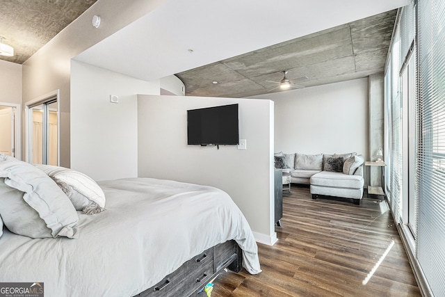 bedroom with a closet, dark hardwood / wood-style floors, multiple windows, and ceiling fan