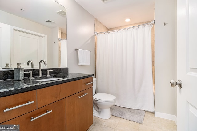 bathroom with toilet, vanity, and tile patterned floors