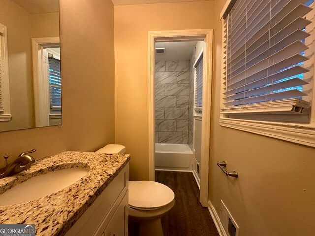 full bathroom featuring hardwood / wood-style floors, vanity, toilet, and tiled shower / bath