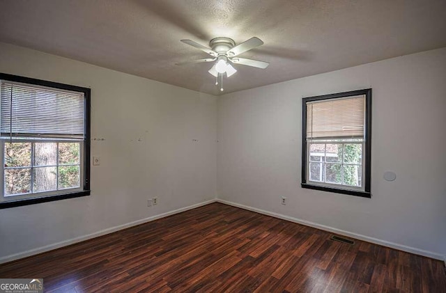 empty room featuring a textured ceiling, ceiling fan, and dark wood-type flooring