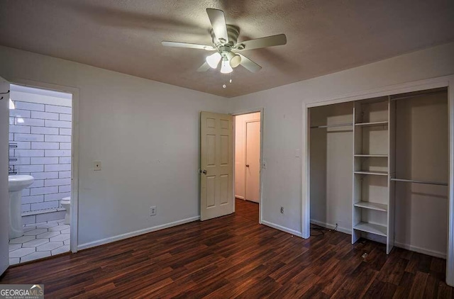 unfurnished bedroom with a textured ceiling, ceiling fan, a closet, and dark hardwood / wood-style floors