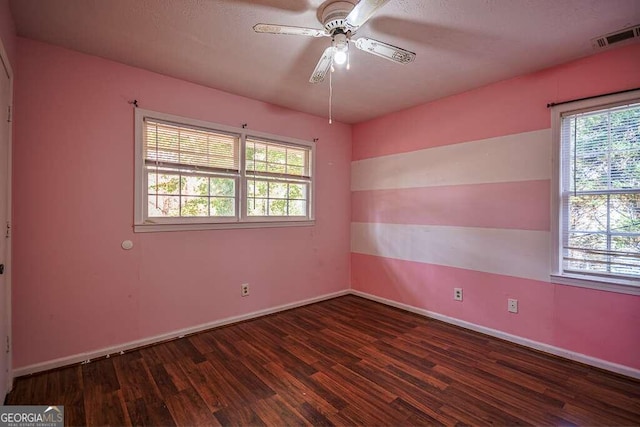 unfurnished room with a textured ceiling, dark wood-type flooring, ceiling fan, and a healthy amount of sunlight