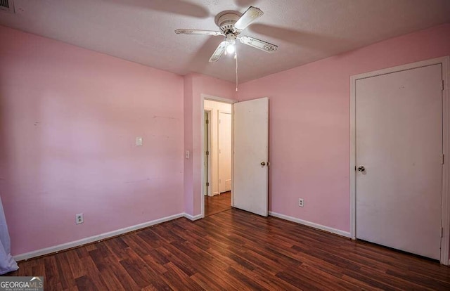 unfurnished bedroom with a textured ceiling, ceiling fan, and dark wood-type flooring