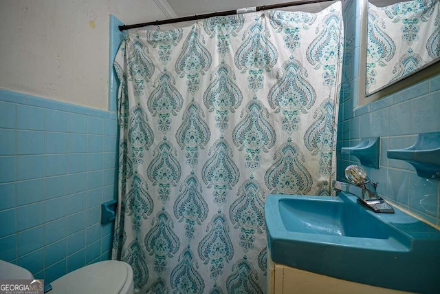 bathroom featuring a shower with shower curtain, vanity, toilet, and tile walls