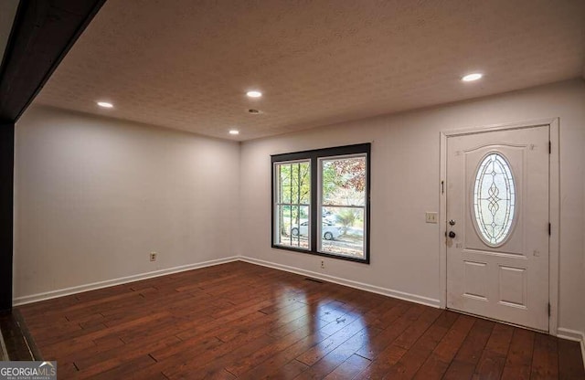 foyer with dark wood-type flooring and a textured ceiling