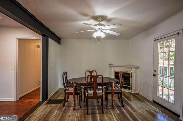 dining area with ceiling fan, plenty of natural light, dark wood-type flooring, and a textured ceiling