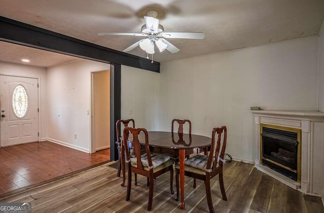 dining room featuring beamed ceiling, ceiling fan, and dark wood-type flooring