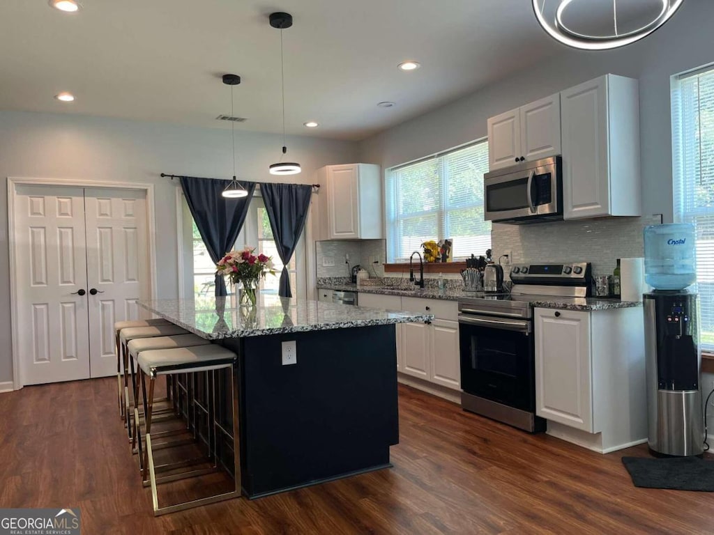 kitchen featuring white cabinets, dark hardwood / wood-style floors, a kitchen island, and stainless steel appliances