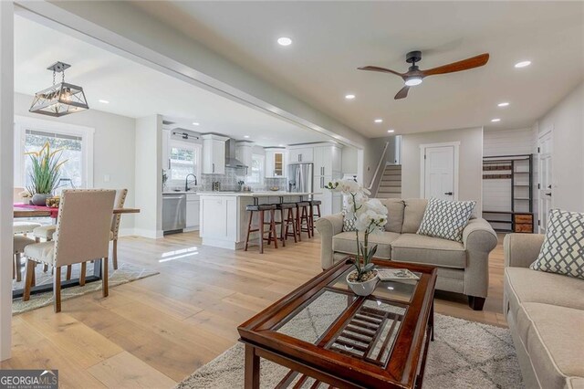 living room featuring ceiling fan, sink, and light wood-type flooring