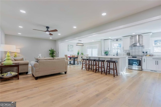 living room featuring ceiling fan, sink, and light hardwood / wood-style floors