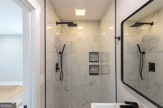 bathroom with a tile shower and hardwood / wood-style flooring