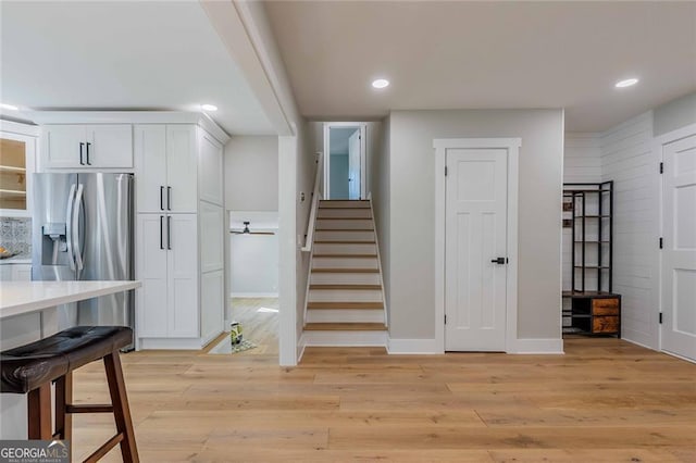 kitchen featuring white cabinets, stainless steel refrigerator with ice dispenser, and light wood-type flooring