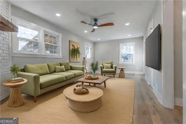 living room with a fireplace, light hardwood / wood-style flooring, and ceiling fan