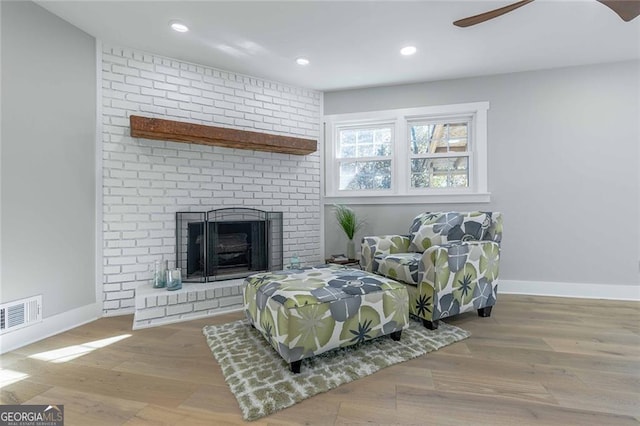 sitting room with ceiling fan, a fireplace, and light hardwood / wood-style flooring