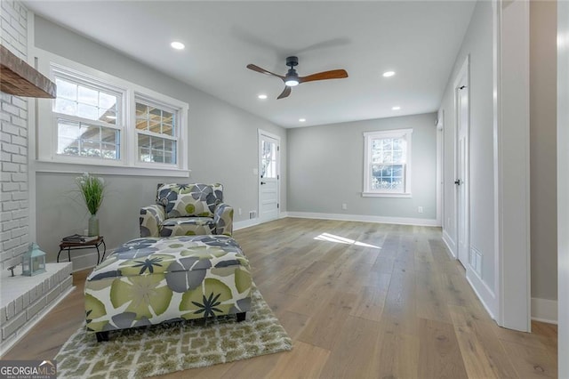 sitting room with a fireplace, light wood-type flooring, and ceiling fan